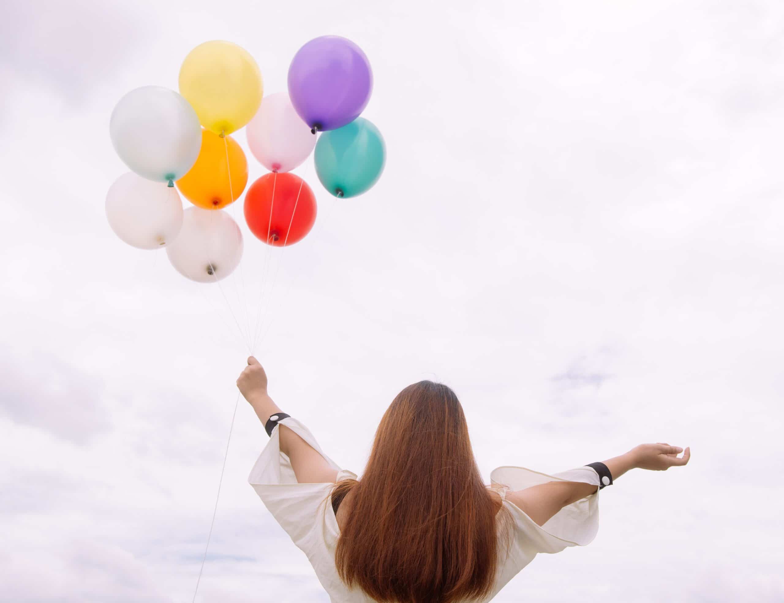 Mujer alzando globos al cielo.